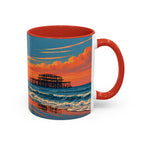A ceramic mug with a red handle and red interior, featuring a printed beach scene at sunset with blue ocean waves, orange clouds, and a pier. The mug is shown on a clean white background.